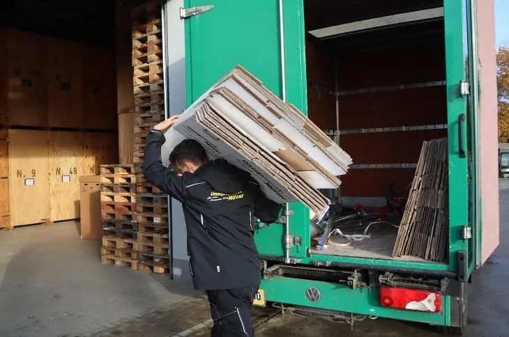 umzugshelfer traegt holzplatten aus umzugswagen
